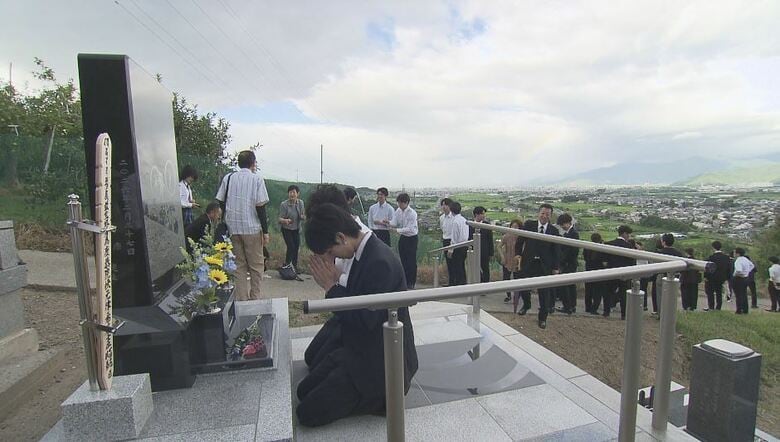 律希さんの墓に手を合わせる友人たち