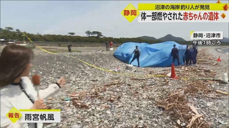 警察がブルーシートの中で鑑識作業を行っている