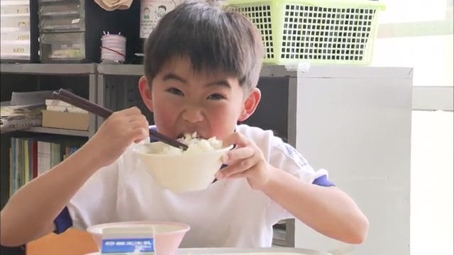 給食をほおばる児童