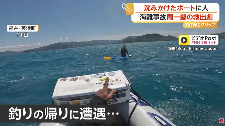 沈みかけたボートで立ち尽くす男性（11日、福井・美浜町）