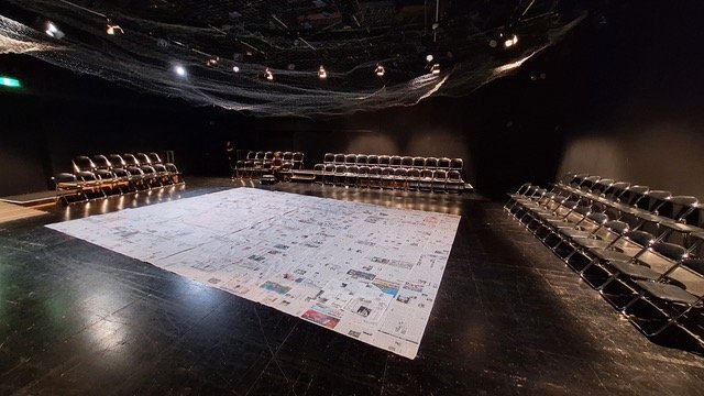 劇場の床に新聞紙が敷き詰められている