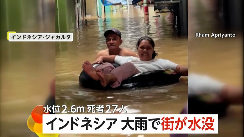 浸水した街で浮き輪に乗って避難する女性