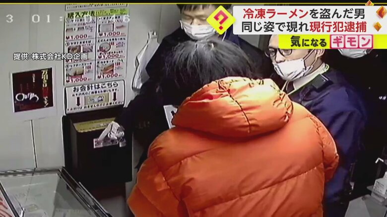 容疑者に対して何かを話しながら料金箱を指さす警察官