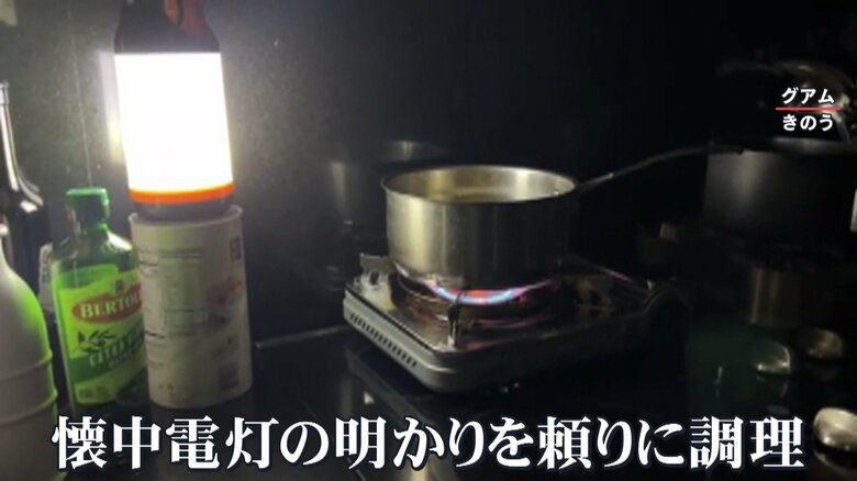 停電のため、懐中電灯とカセットコンロで調理する現地の男性
