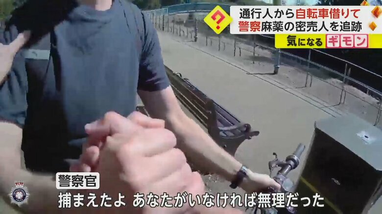 自転車を借りた人と握手を交わす警察官