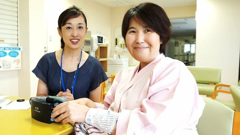 VADを装着している容子さん（右）植え込み型補助人工心臓はケーブルでバッテリーと繋がっている　（左は筆者）