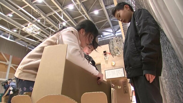 「段ボールベッド」の組み立て方を教える智桜さん