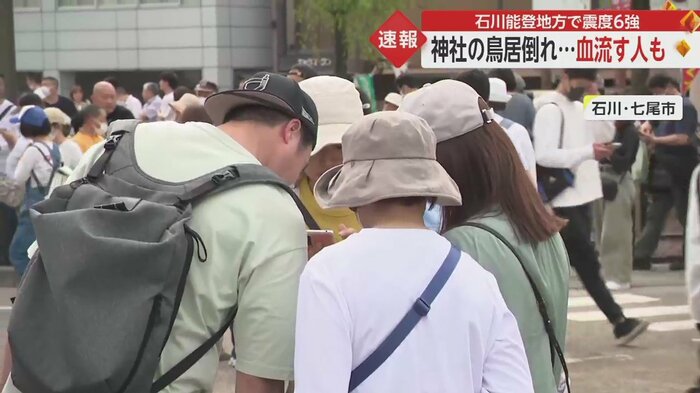 スマホで地震の情報を確認している人々