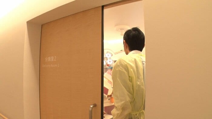 感染対策のマスクや防護服を着けてから、分娩室へ入る光さん
