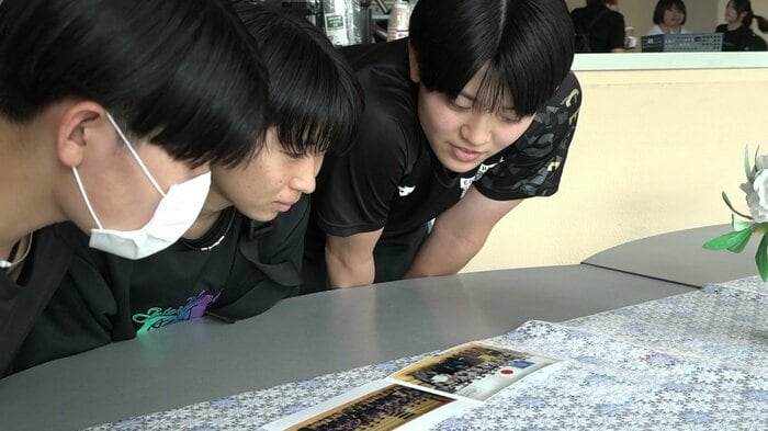 井上さんとの写真を見つめる選手たち