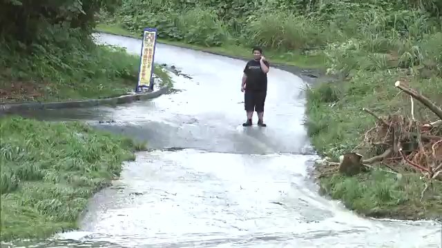 「洗い越し」の対岸からインタビューにこたえる松崎さん