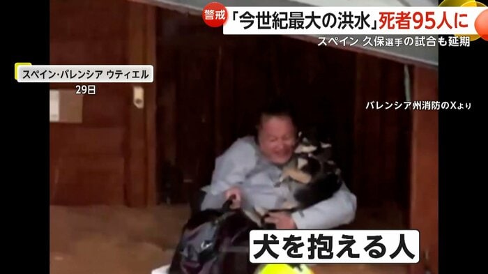 下半身が水に浸かった状態で犬を抱き抱える人