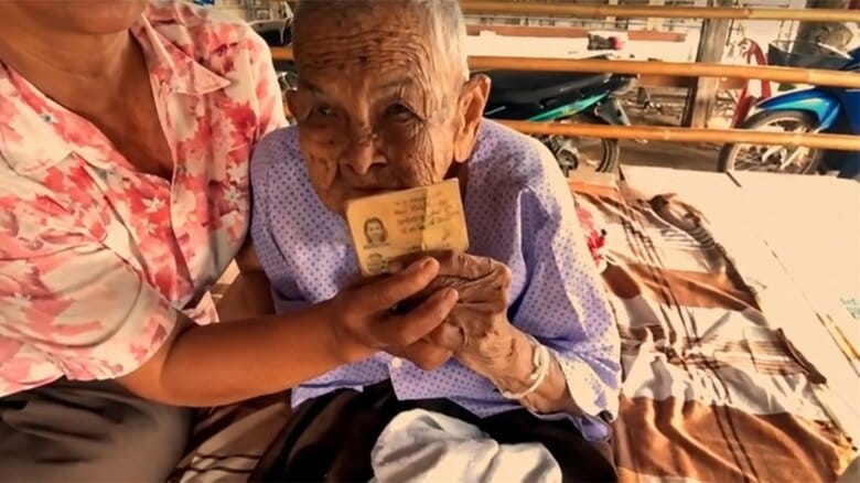 「130歳」の根拠となっている古い身分証を手にするセーンさん
