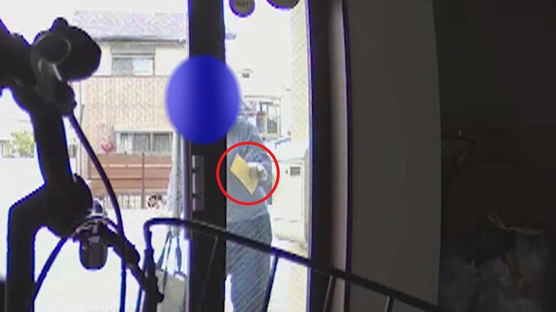 右手に大きなバッグ、左手には茶封筒を持った人物