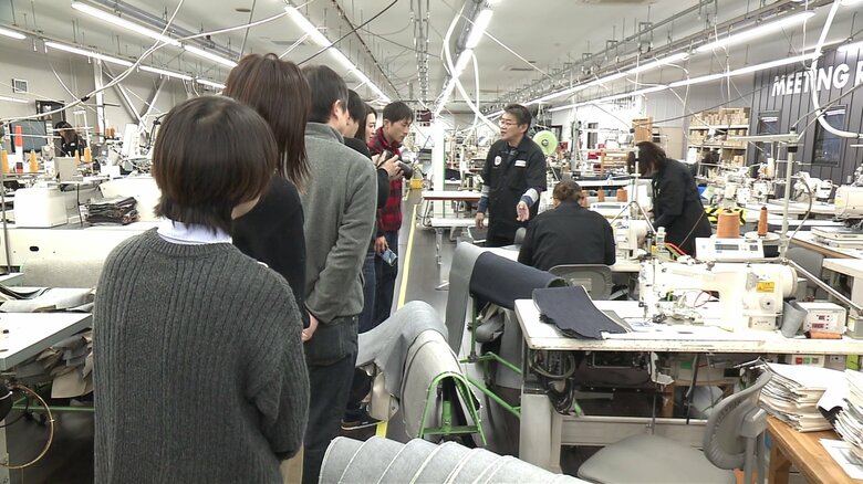 作業工程の説明を受ける見学ツアーの参加者