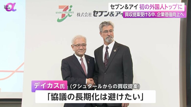 退任する井阪隆一氏と握手する新社長のスティーブン・デイカス氏（64）