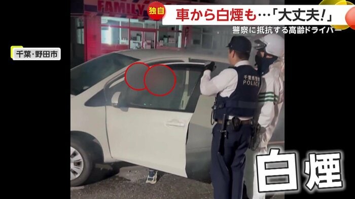 薄っすらと白煙があがる中で話を聞く警察(提供:ハリソン青木)