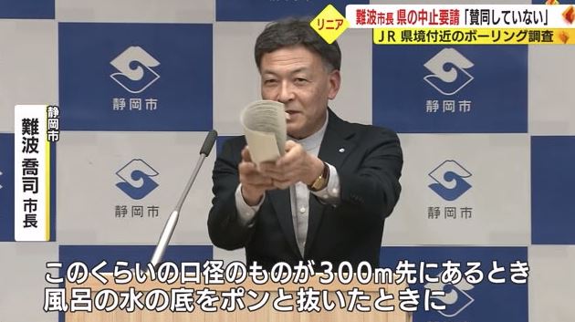 資料をまるめボーリング調査の口径を説明する難波市長
