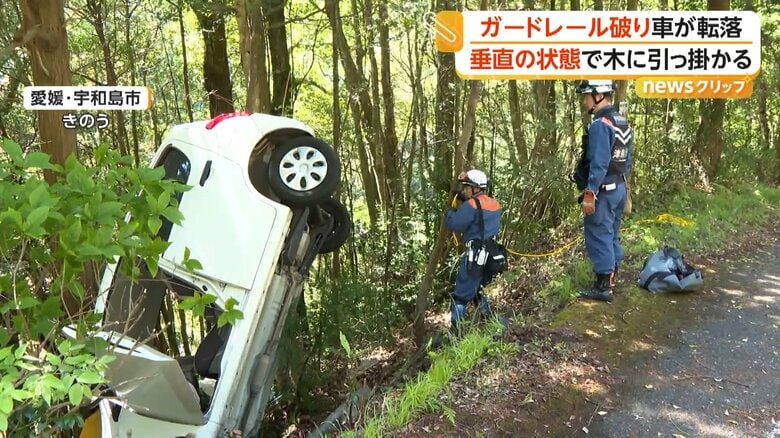 ほぼ垂直の状態で立ち木に引っかかり、ドアは開いたままの車
