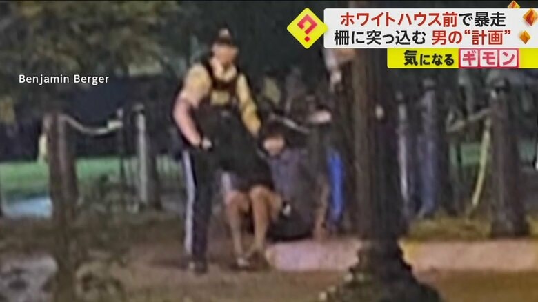 男が警察官の隣で座り込んでいる