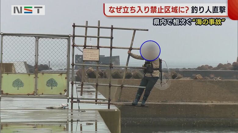 立ち入り禁止区域から戻ってくる人。海に突き出た柵をまたいでいる。落ちたら危ない