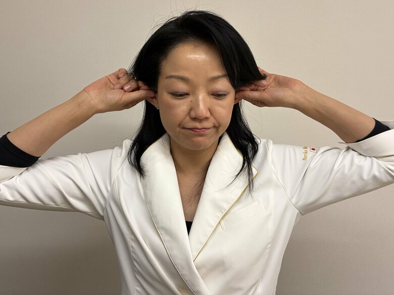 耳を引っ張ることで周りの筋肉がほぐれる（特集班撮影）