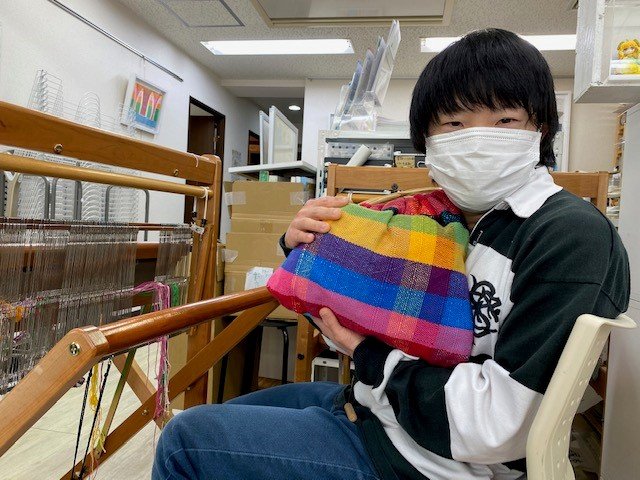 自作の織物作品を持つ待寺優さん