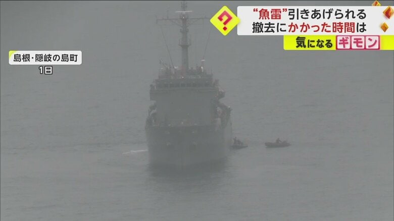 船上から”魚雷”らしき物が引きあげられるのを見守る人々
