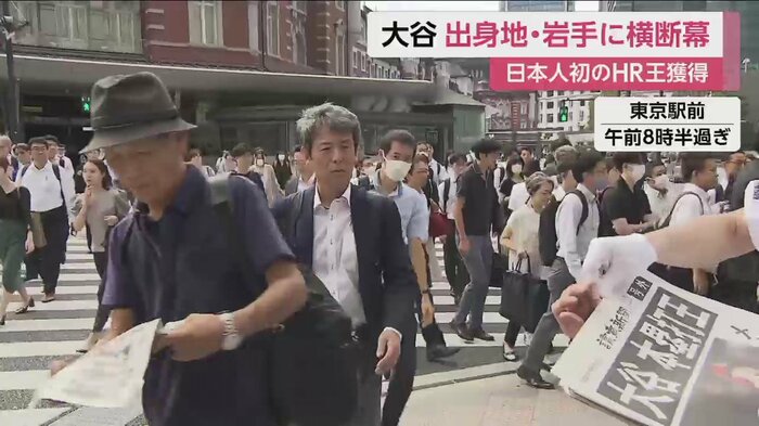 ホームラン王獲得の号外が配られ、人々が次々と手に取っていく(東京駅前 2日午前8時半すぎ)