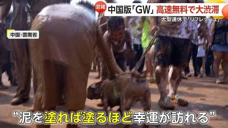 犬にまで泥を塗る中国・雲南省の伝統的民俗行事の参加者たち