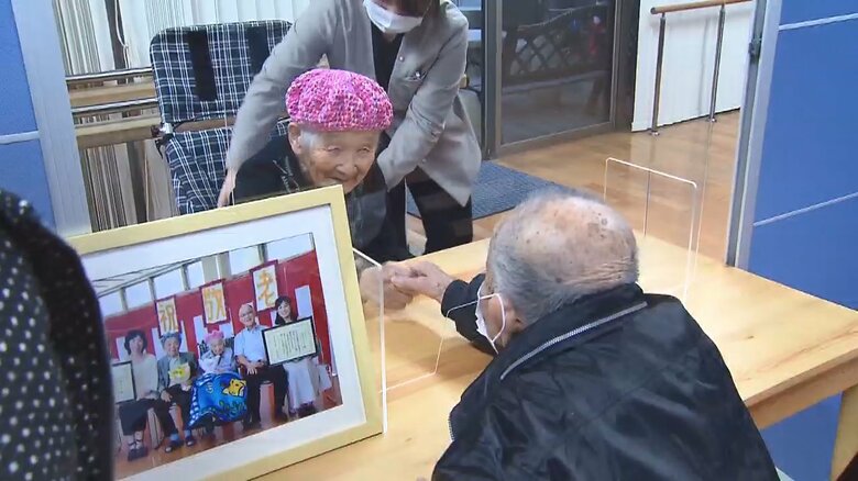 2カ月ぶりの面会で握手する忠義さんとシヅ子さん