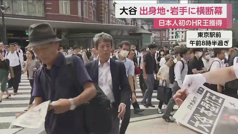 ホームラン王獲得の号外が配られ、人々が次々と手に取っていく（東京駅前　2日午前8時半すぎ）