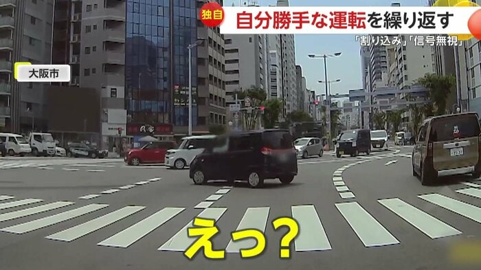 右折レーンから赤信号を無視して左折する黒い車