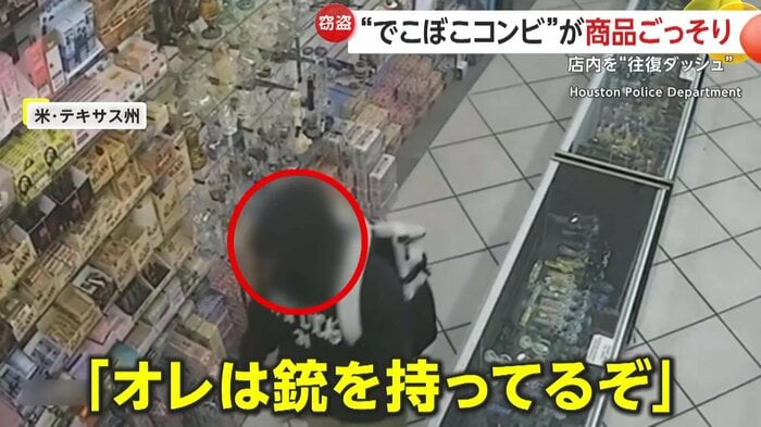 店員を脅す大柄な強盗犯