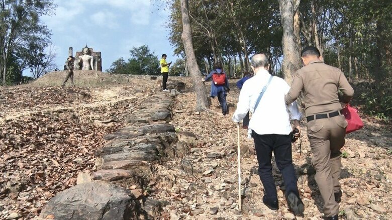 事件現場「ワット・サパーンヒン」　地元の警察官に支えられ杖を使い山道を登る康明さんら
