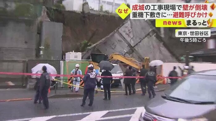 黄色い工事車両が、倒れた壁の下敷きになっているのが見える