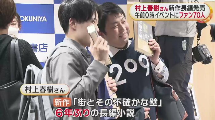 新作を購入し、記念撮影するファンたち