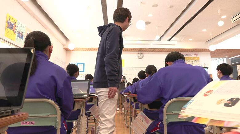 机の間を気を付けながら歩く先生