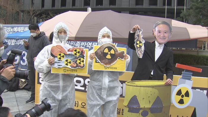 4月13日のソウル・日本大使館前で行われた環境団体の日本批判パフォーマンス。防護服を着込んでいる