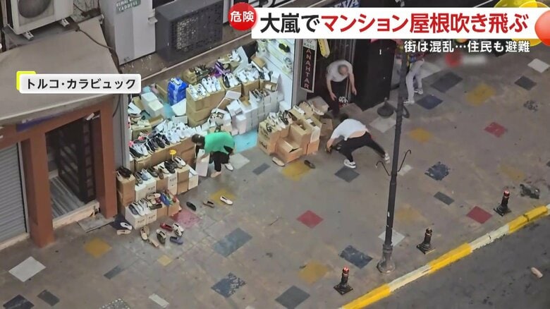 強風に飛ばされた店の商品を片付ける人たち