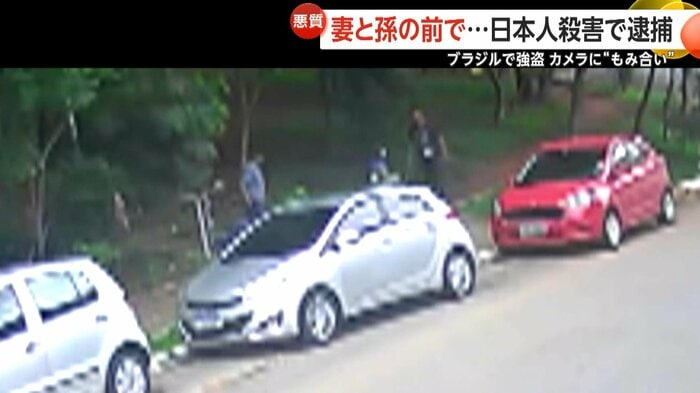 赤い車に向かう家族連れに男が近寄る