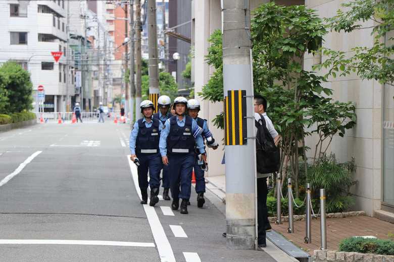 電柱のうしろに私服警察