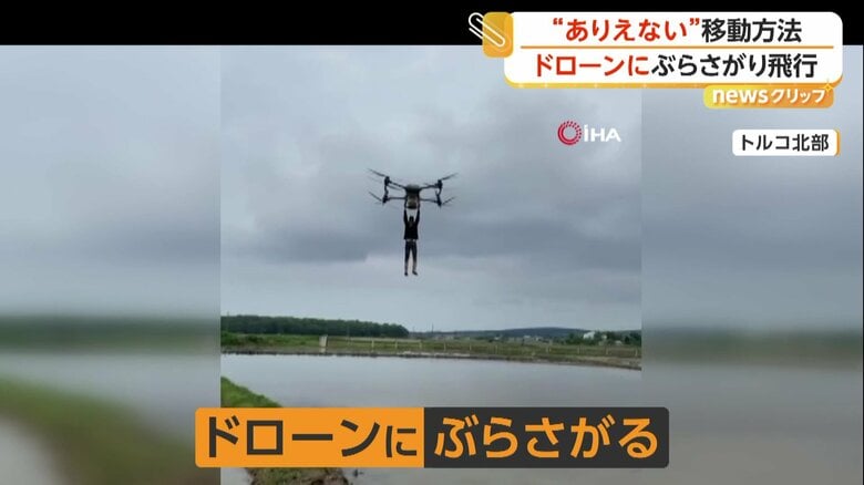 男性がぶらさがったまま上昇するドローン