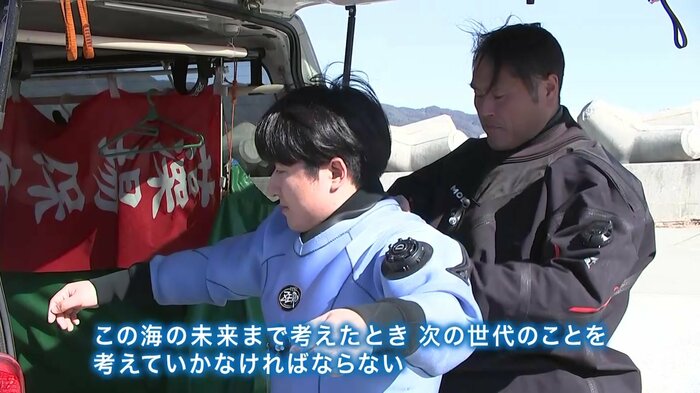 ダイビングスーツを着せる佐藤寛志さん