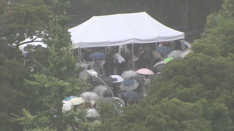雨の中、献花台には行列ができていた（15日撮影）