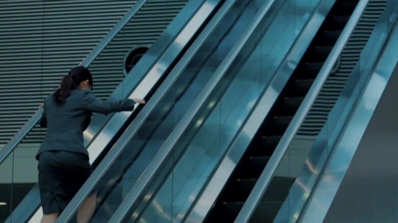 下りのエスカレーターを必死に上る女性