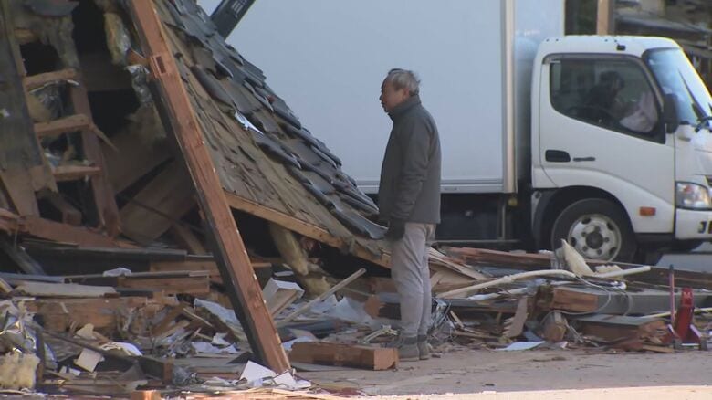 倒壊した自宅兼店舗を見つめる楠さん（1月2日取材）