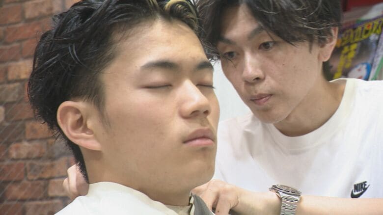 息子の髪を切る父親の善行さん