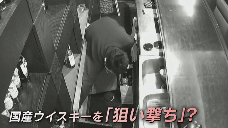 防犯カメラが捉えた容疑者が酒瓶を紙袋にいれる様子