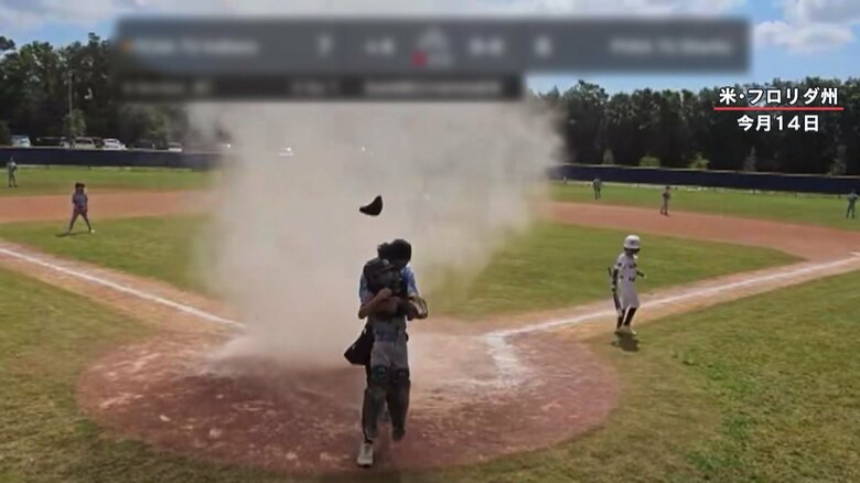 少年を風から守るように背を向けて、救出する